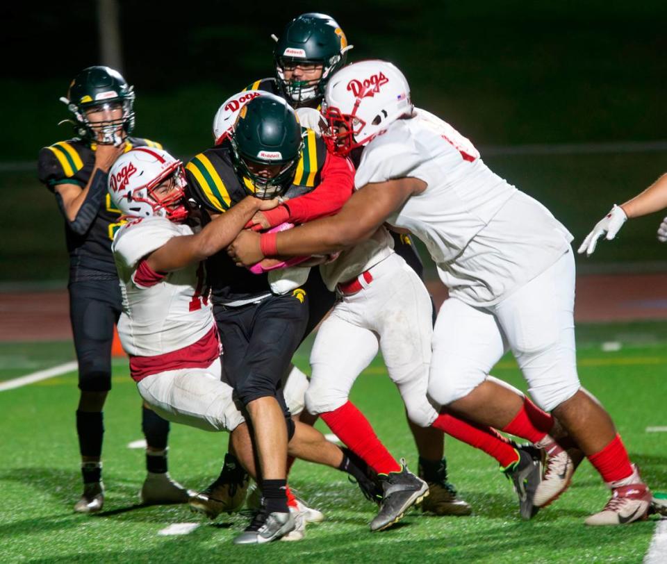 Ezekiel Suarez, 1, of Davis High gets taken down by the Ceres High defensive line during a WAC game against Ceres High on Friday Oct. 27, 2023.