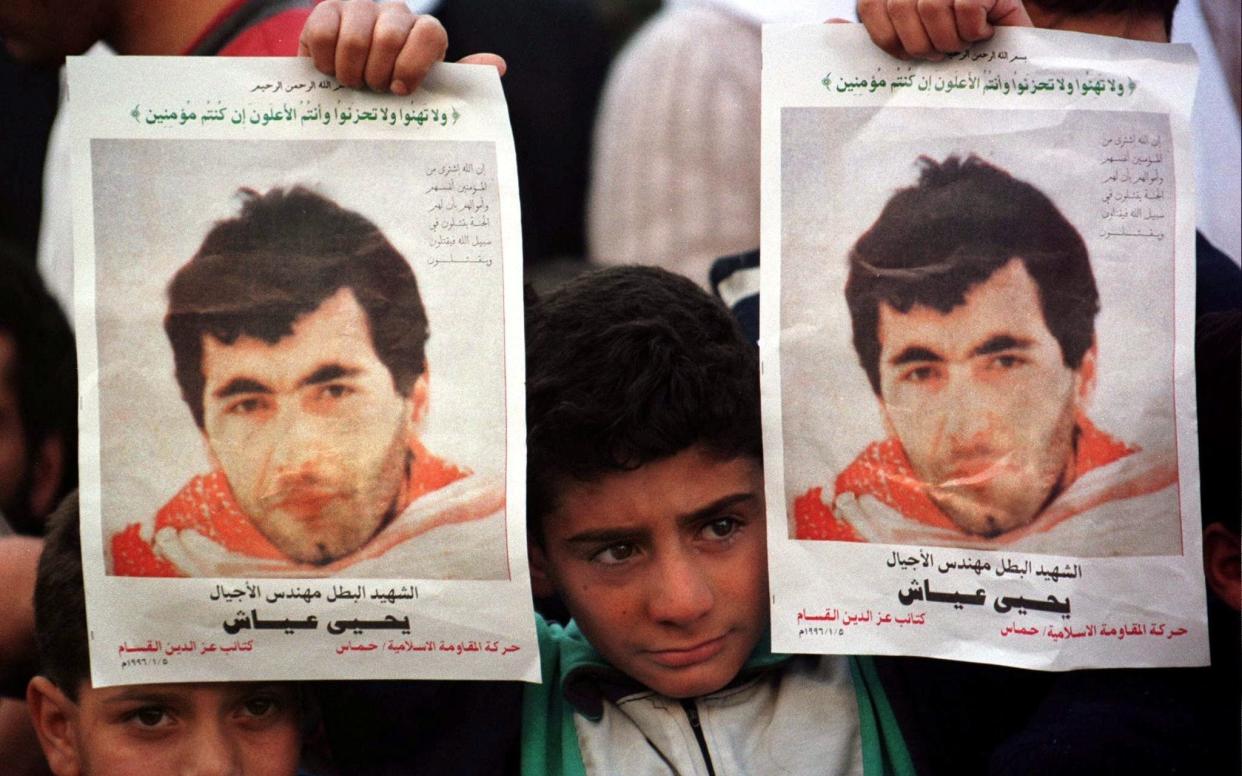 A Palestinian boy holds up posters of Yahya Ayyash