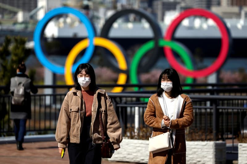 FILE PHOTO: People wearing protective face masks are seen in front of the Giant Olympic rings at the waterfront area at Odaiba Marine Park in Tokyo