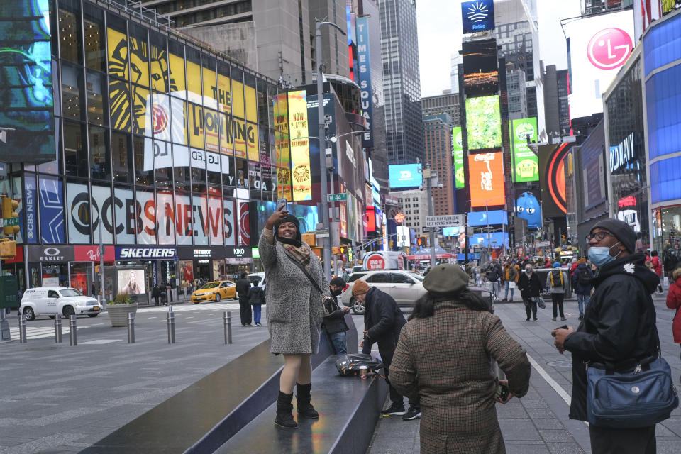 A woman poses for a selfie in Times Square, Monday, Nov. 15, 2021, in New York. Even as visitors again crowd below the jumbo screens in New York’s Times Square, the souvenir shops, restaurants, hotels and entrepreneurs within the iconic U.S. landmark are still reeling from a staggering pandemic. (AP Photo/Seth Wenig)