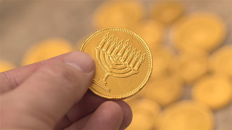 Fingers holding gold gelt coin 