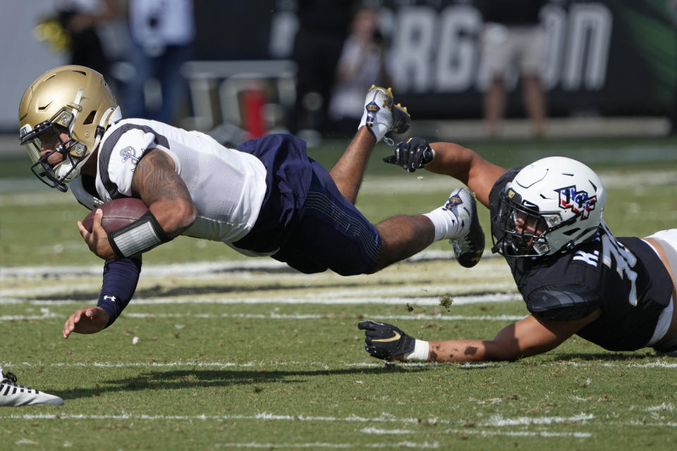Navy quarterback Xavier Arline is stopped after a short gain by Central Florida linebacker Kam Moore during the first half of an NCAA college football game, Saturday, Nov. 19, 2022, in Orlando, Fla. (AP Photo/John Raoux)