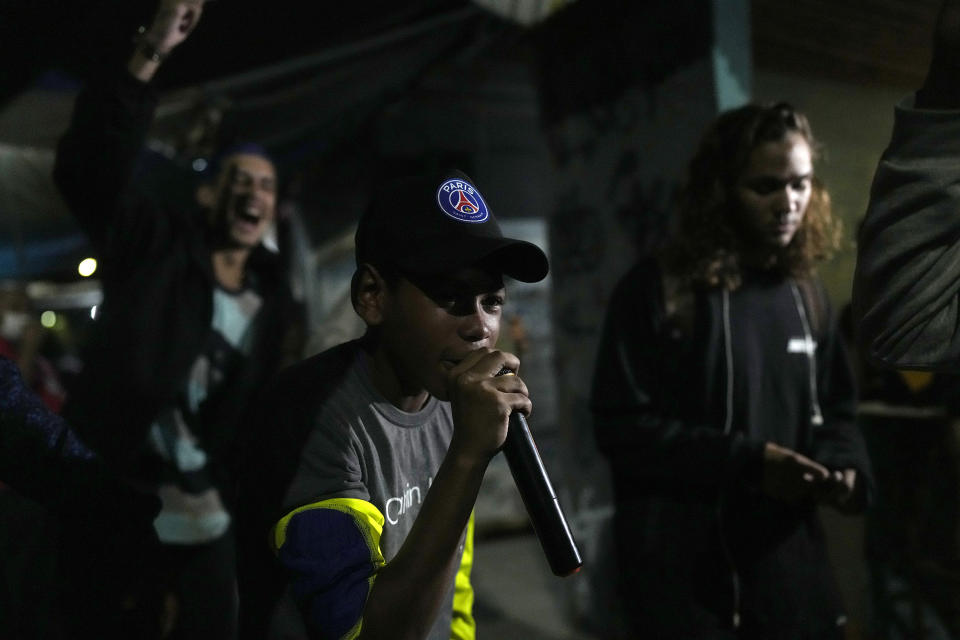 Tavin competes in the Gas Battle rapping event outside a bar in the City of God favela, Rio de Janeiro, Brazil, late Wednesday, Nov. 10, 2021. Rap artists in the favela are starting to compete again since the COVID-19 pandemic curtailed public gatherings, presenting local residents with a show in a sign of a return to normalcy for music lovers. (AP Photo/Silvia Izquierdo)