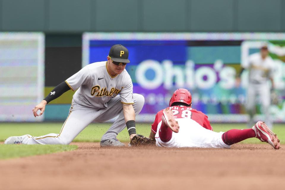 Pittsburgh Pirates shortstop Diego Castillo, center left, tags Cincinnati Reds left fielder Tommy Pham (28) out as he attempts to steal second base during the first inning of a baseball game Thursday, July 7, 2022, in Cincinnati.