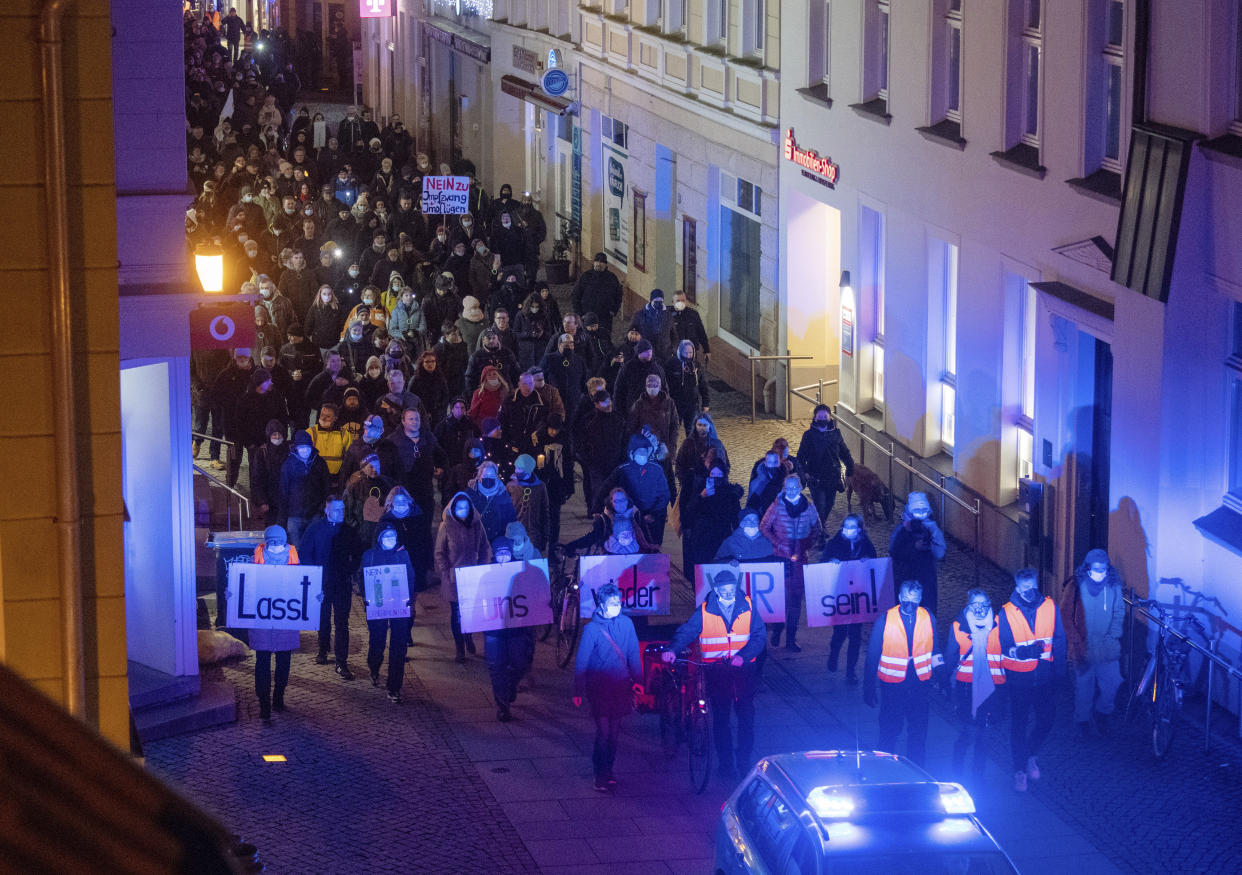 Participants of a demonstration against the Corona measures walk through Greifswald, Germany, Monday evening, Jan. 3, 2022. The protests were directed against the corona policy of the state of Mecklenburg-Western Pomerania and the associated restrictions. Tens of thousands of people took to the streets in scores of German towns and cities for weekly marches that have organizers have labeled ‘strolls’ in an attempt to bypass restrictions on public gatherings. Most of the rallies passed peacefully, though many broke rules on social distancing, prompting officers to intervene. (Stefan Sauer/dpa via AP)