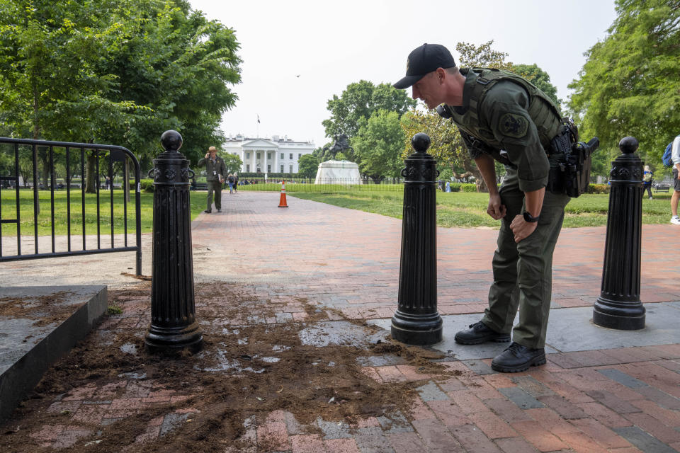 FILE - A U.S. Park Police officer inspects a security barrier for damage in Lafayette Square park near the White House, May 23, 2023, in Washington. A Missouri man pleaded guilty Monday, May 13, 2024, to crashing a rented truck into White House barriers last year. Sai Varshith Kandula drove a large U-Haul truck onto a sidewalk, sending pedestrians running for safety, before ramming it into metal bollard barriers that prevent vehicles from entering Lafayette Square. (AP Photo/Alex Brandon, File)