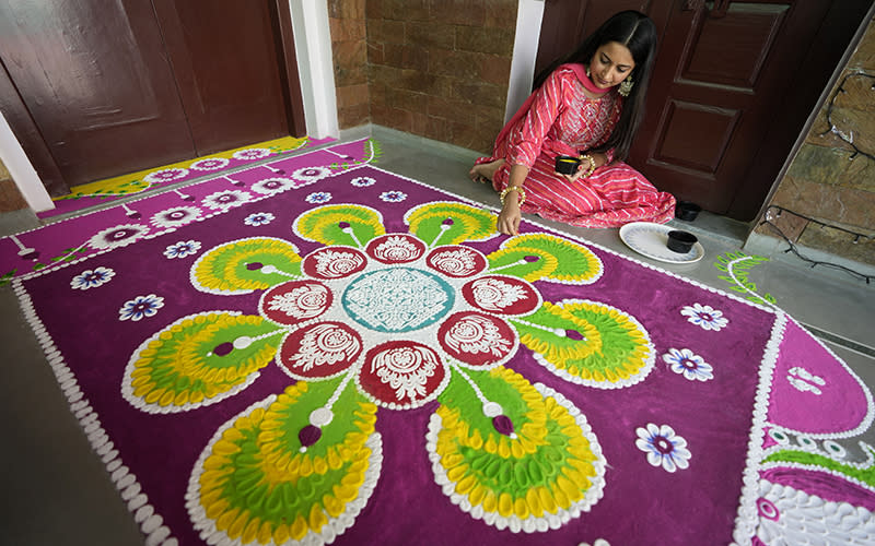 A girl makes a rangoli, a hand decorated pattern on the floor, as part of Diwali festivities