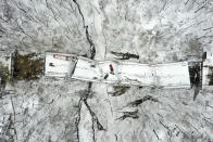 In this aerial image taken with a drone, vehicles rest on a bridge following its collapse, Friday Jan. 28, 2022, in Pittsburgh. The bridge spanning a ravine collapsed, requiring rescuers to rappel nearly 150 feet, while others formed a human chain to help rescue multiple people from a dangling bus. The collapse early Friday came hours before President Joe Biden was to visit the city to press for his $1 trillion infrastructure bill, which includes bridge maintenance. (AP Photo/Gene J. Puskar)
