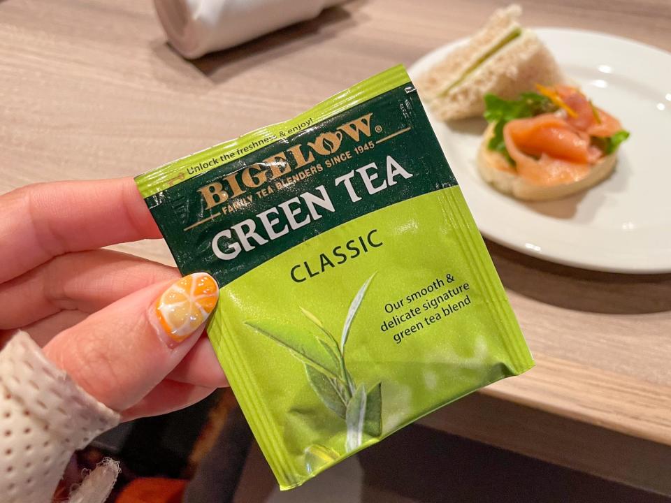 The author's hand holding a packet of Bigelow green tea.