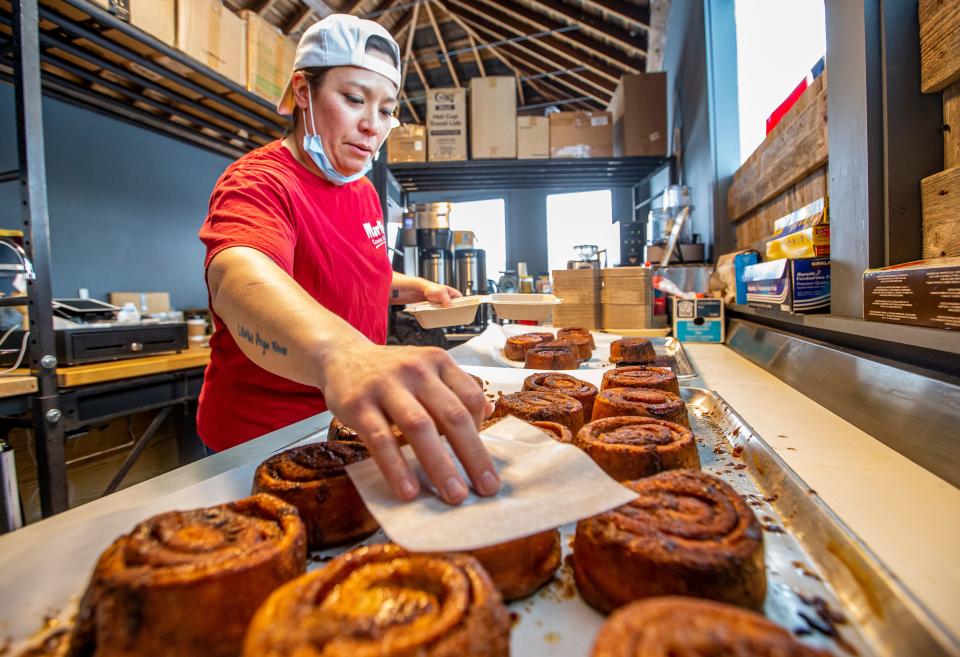 Lise Gustavsen grabs a Norwegian cinnamon roll off a tray inside Gustavsen Cafe on Tuesday, Jan. 10, 2021, in Buchanan.