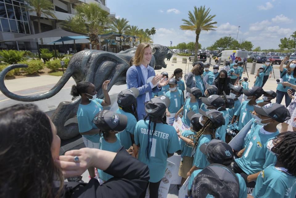 Top draft pick Trevor Lawrence applauds the students from Long Branch Elementary School who greeted him and his wife upon their arrival in Jacksonville, Fla.,  Friday, April 30, 2021. (Bob Self/The Florida Times-Union via AP)