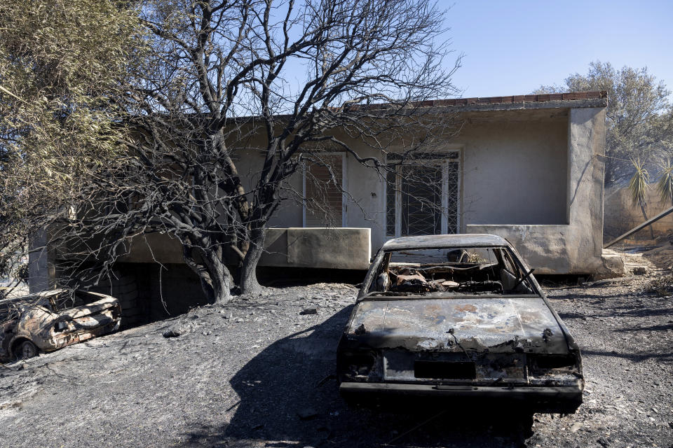 Los restos de un auto consumido por el fuego permanecen en el patio de una vivienda tras el paso de un incendio forestal en el área de Keratea, al sureste de Atenas, Grecia, el domingo 30 de junio de 2024. (AP Foto/Yorgos Karahalis)