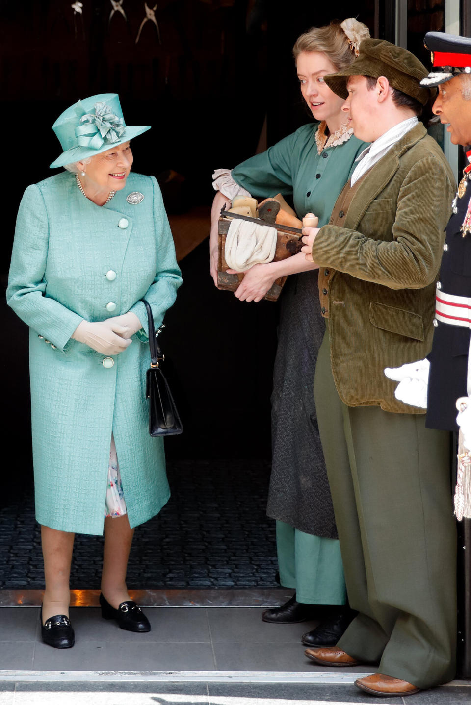 Queen Elizabeth II talks to actors in period costume as she visits a replica of one of the original Sainsbury's stores in Covent Garden 