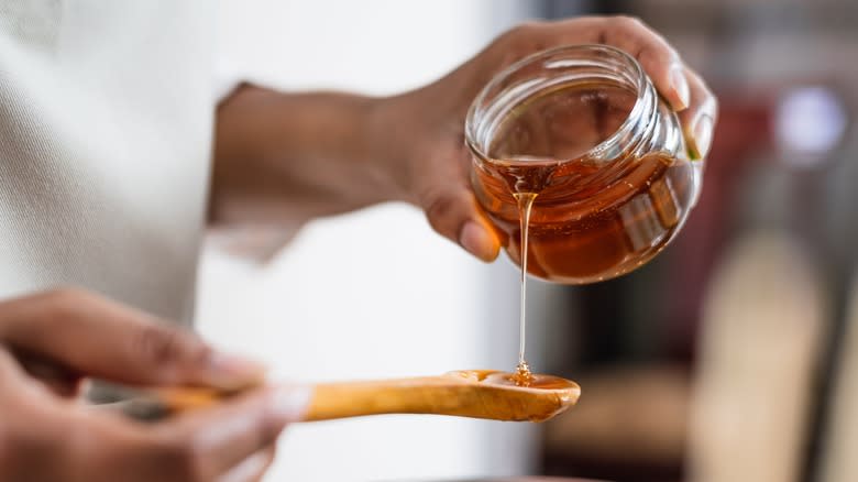 pouring honey onto wooden spoon