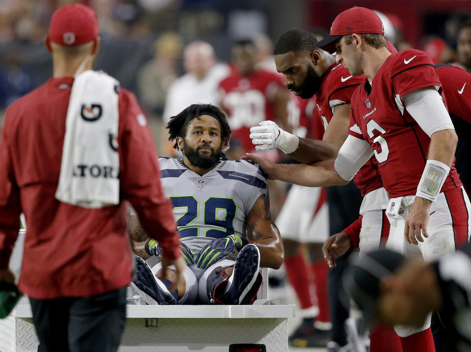 Seahawks defensive back Earl Thomas is greeted by Cardinals players as he leaves the field after breaking his leg during the second half. (AP)