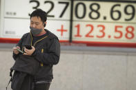 A person walks past an electronic stock board showing Japan's Nikkei 225 index at a securities firm Tuesday, Nov. 14, 2023, in Tokyo. Asian shares were mostly higher Tuesday ahead of potentially market-moving developments, including a U.S.-China summit and data releases from the U.S., Japan and China. (AP Photo/Eugene Hoshiko)