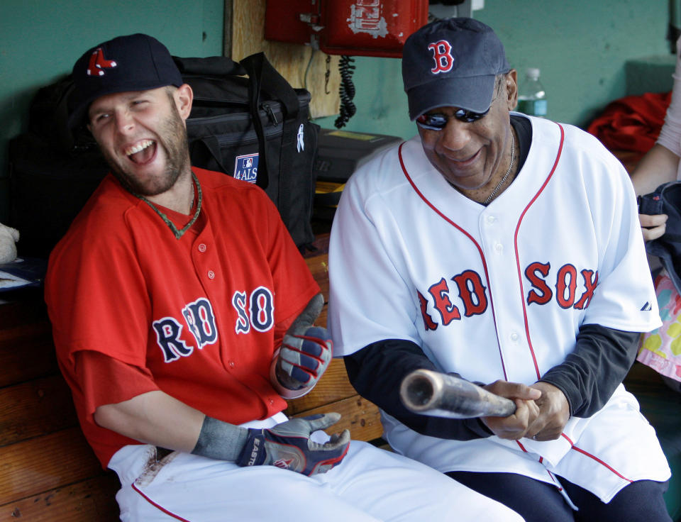 FILE - In this July 10, 2009, file photo, Boston Red Sox second baseman Dustin Pedroia, left, laughs as he jokes with comedian Bill Cosby while sitting in the dugout prior to a baseball game against the Kansas City Royals at Fenway Park in Boston. (AP Photo/Charles Krupa, File)