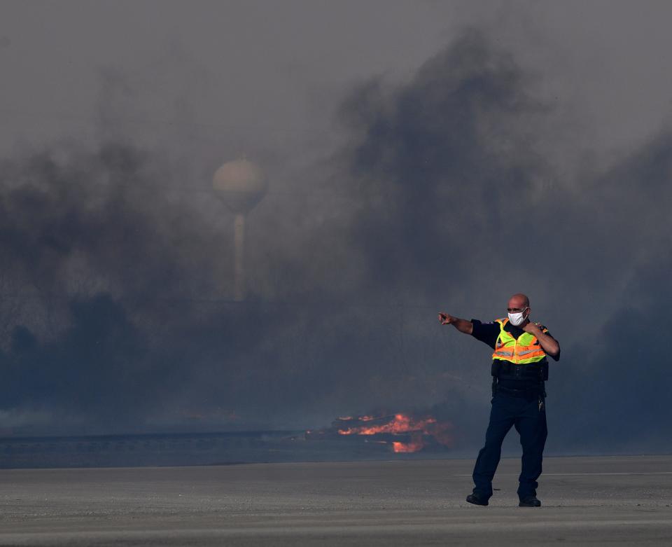 An Abilene Fire Department fire marshal directs traffic to turn around on South First Street at the Old Highway 80 intersection Thursday. The grass fire jumped South First Street and threatened a mobile home park, which was evacuated.