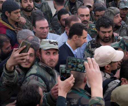 Syrian army soldiers take pictures with their mobile phones of Syrian President Bashar al-Assad in eastern Ghouta, Syria, March 18, 2018. SANA/Handout via REUTERS