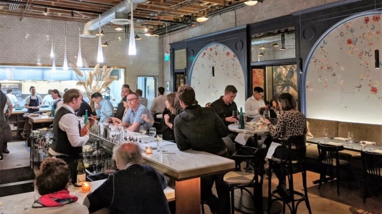 patrons eating at long tables inside dining room