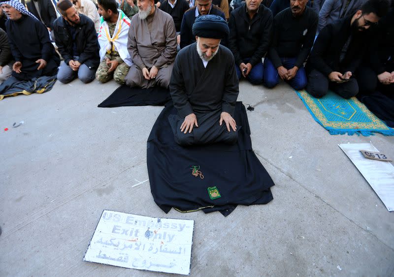 A cleric prays during a protest outside the main gate of the U.S. Embassy in Baghdad
