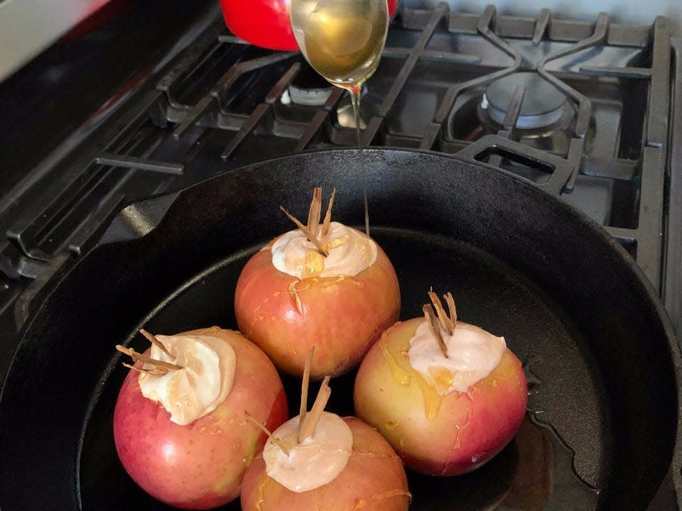 honey drizzled over baked apples in a cast iron skillet