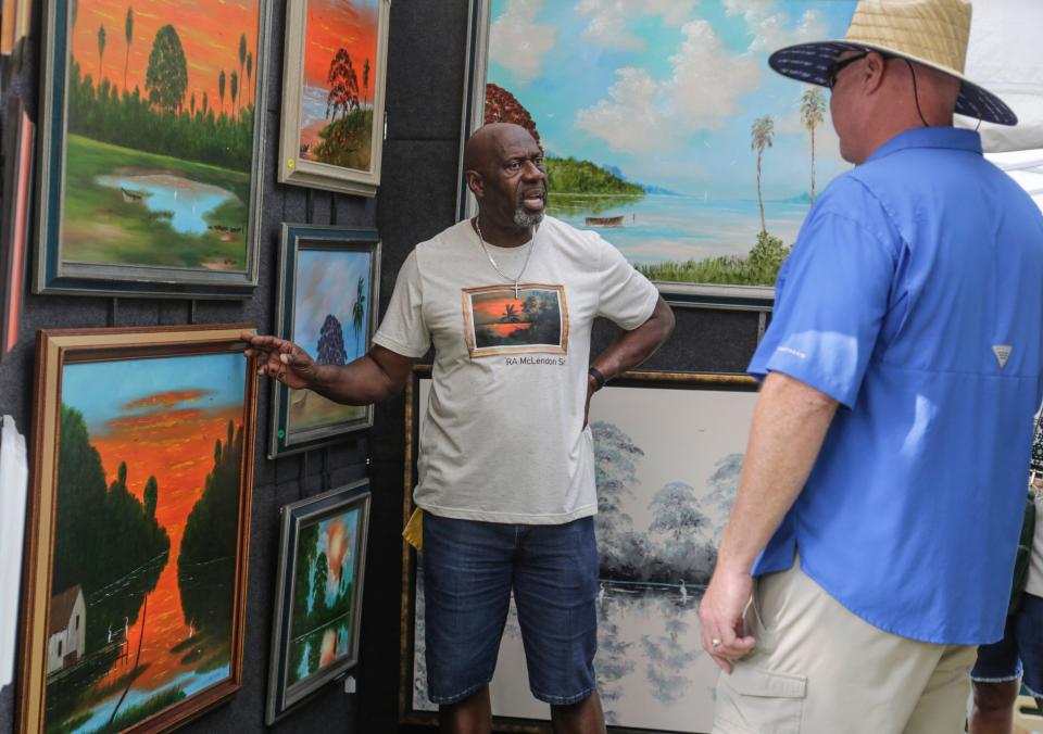 Florida Highwayman Ray McLendon of Vero Beach explains his artwork to visitors at Mayfaire on Saturday.
