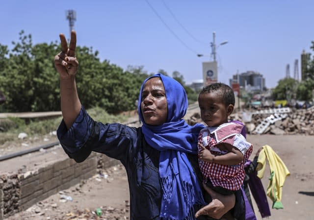 A protester holding her child in a street leading to the sit-in outside the military headquarters in Khartoum