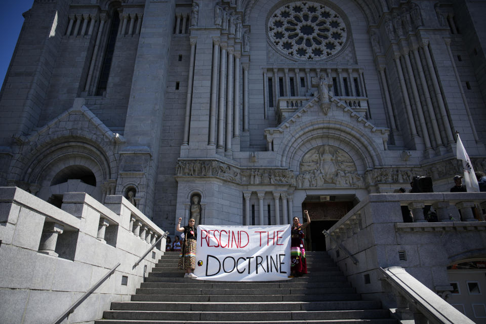 Sarain Fox, right, and Chelsea Brunelle of the Batchewana First Nation demonstrate outside the mass presided over by Pope Francis at the National Shrine of Saint Anne de Beaupre, Thursday, July 28, 2022, in Saint Anne de Beaupre, Quebec. Pope Francis is on a "penitential" six-day visit to Canada to beg forgiveness from survivors of the country's residential schools, where Catholic missionaries contributed to the "cultural genocide" of generations of Indigenous children by trying to stamp out their languages, cultures and traditions. (AP Photo/John Locher)