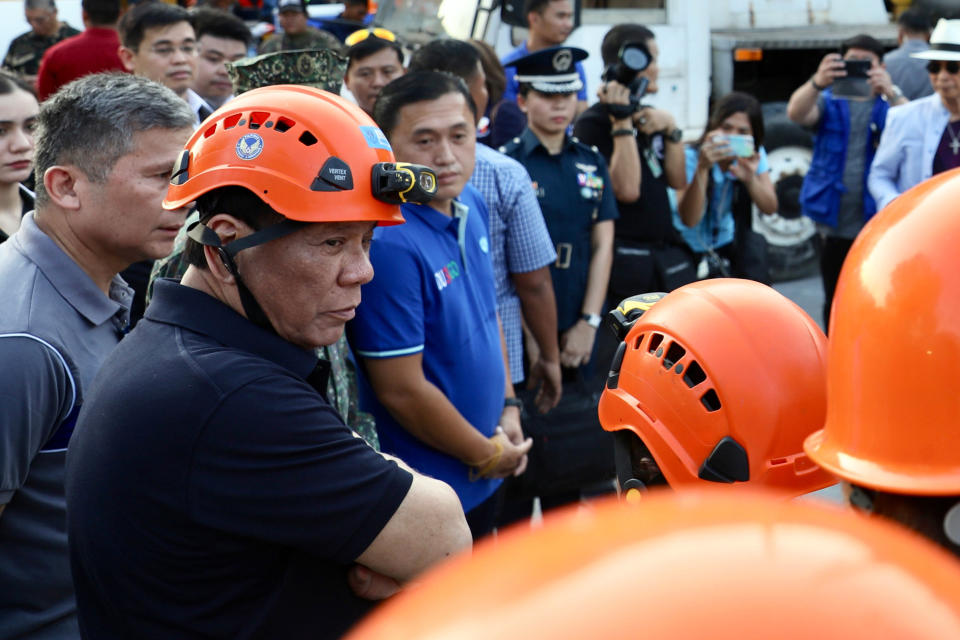 In this April 23, 2019, photo released by the Malacanang Presidential Photographers Division, Philippine President Rodrigo Duterte, bottom left, talks to rescuers as he visits an earthquake-damaged building where operations continue for trapped people in Porac town, Pampanga province, northern Philippines. The Philippine national police chief says investigators have summoned the owner of a four-story supermarket that collapsed in a powerful earthquake and trapped dozens of people. (Richard Madelo/Malacanang Presidential Photographers Division via AP)