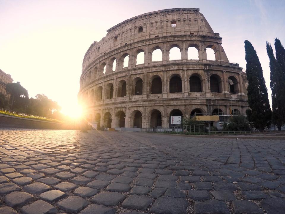 Rome's Colosseum with the sun shining in the back of it.