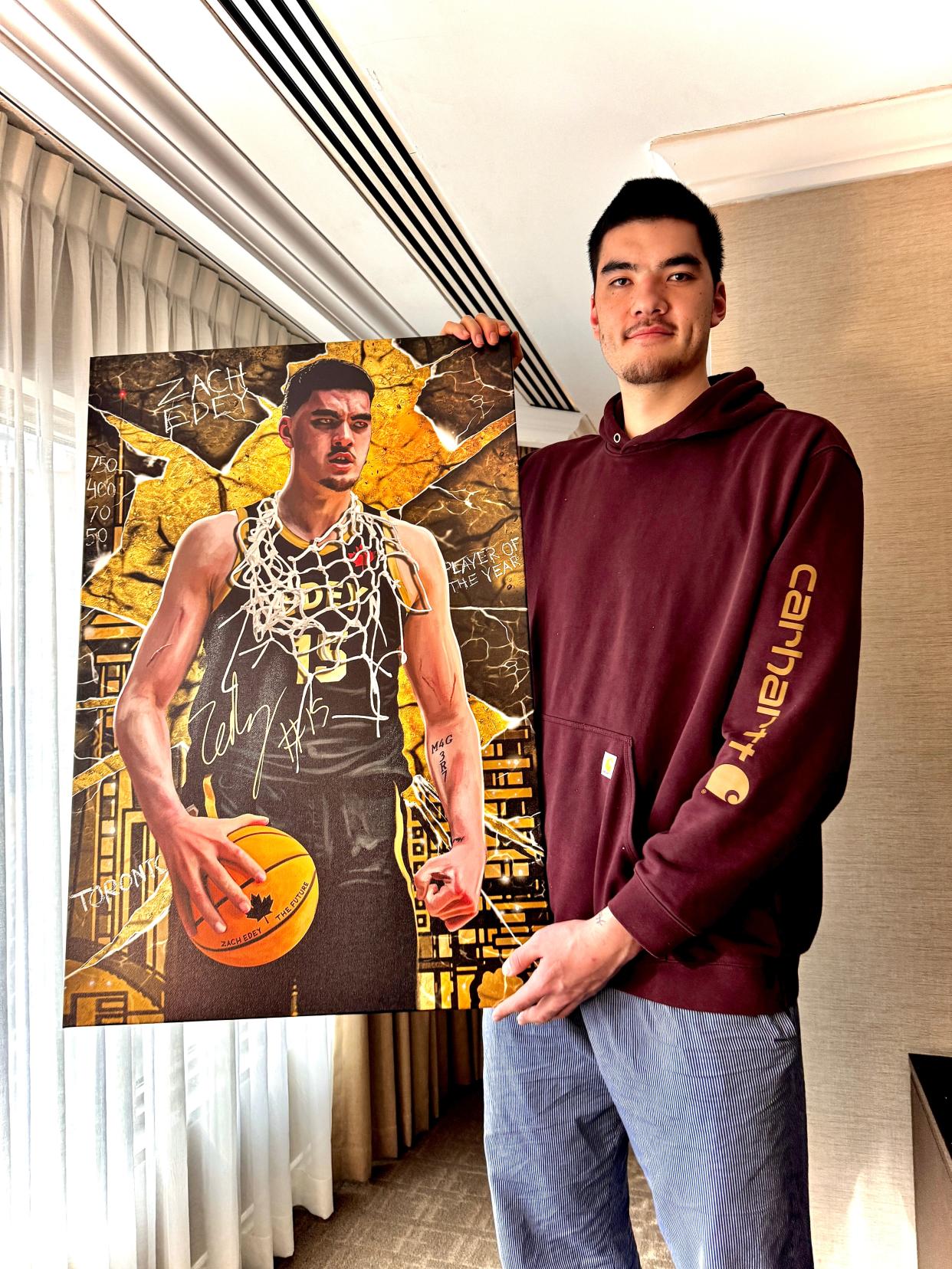 Purdue men's basketball star Zach Edey stands with a poster of himself.