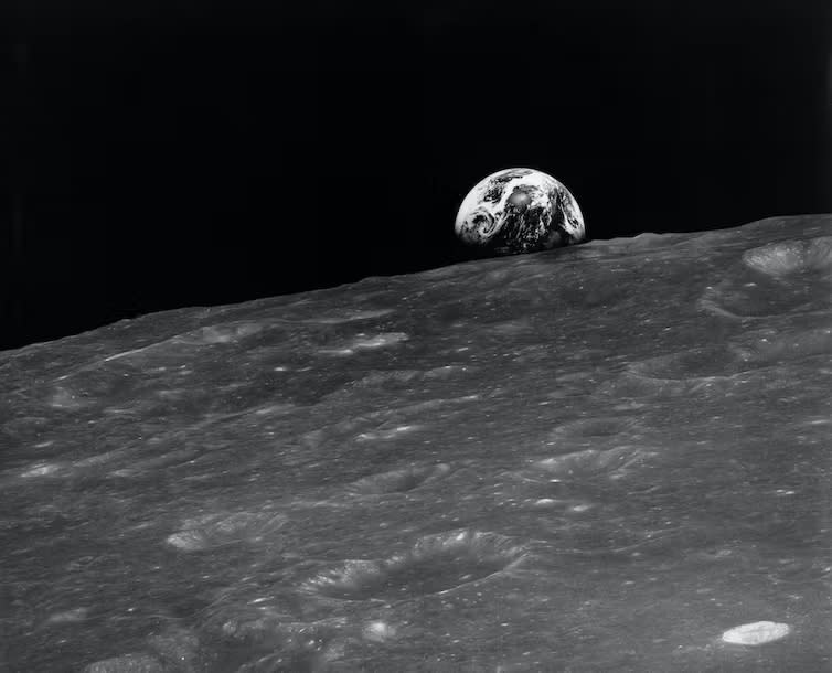 A black and white image of the Earth rising over the moon