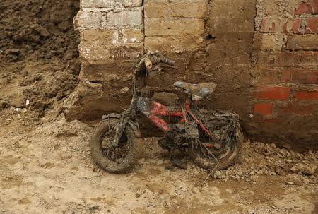 A children's bike leans against a wall covered in mud after rivers breached their banks due to torrential rains, causing flooding and widespread destruction in Carapongo Huachipa, Lima, Peru, March 24, 2017. REUTERS/Mariana Bazo