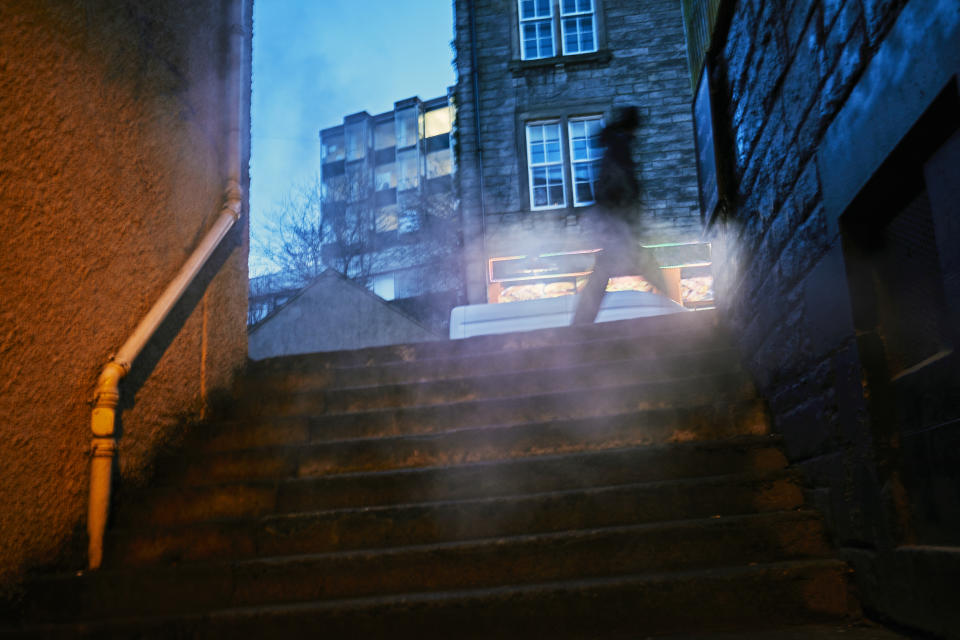 Photographing through exhaust vent steam, condensation from building heating that is illuminated by orange street light. Edinburgh at night has an ominous film noir atmosphere