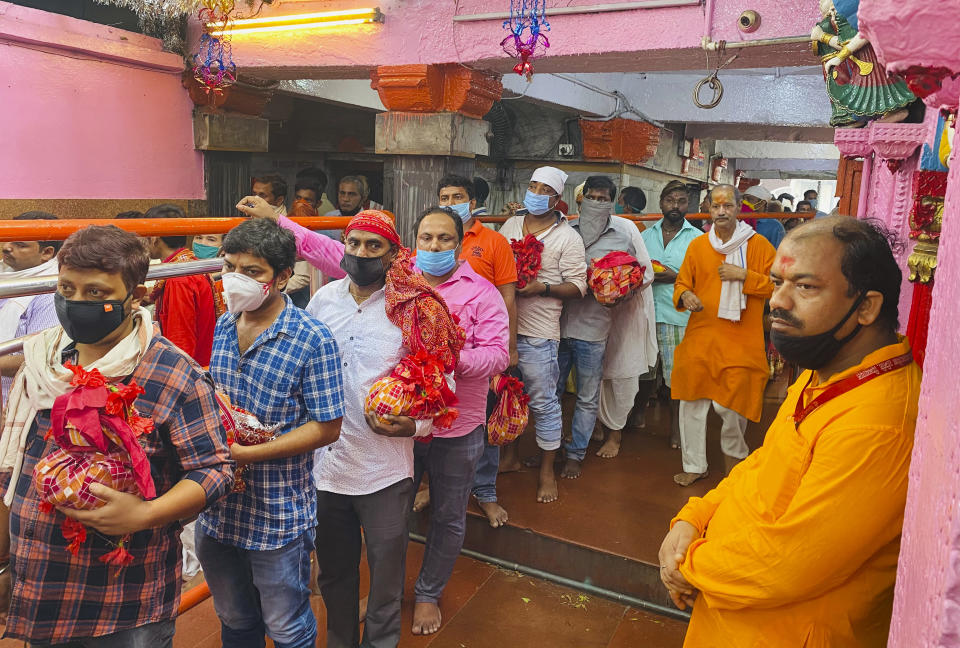 FILE- In this Saturday, Oct. 17, 2020, file photo, devout Hindus wearing masks as a precaution against the coronavirus stand in a queue to offer prayers at the Vindhyavasini temple in Mirzapur in the northern Indian state of Uttar Pradesh. The Hindu festival season that draws tens and thousands of people, packed together shoulder-to-shoulder in temples, shopping districts and congregations, has lead to fears and a sense of foreboding among health experts who warn of a whole new cascade of infections, further testing India’s already battered healthcare system. The fears of such a prospect, in fact, prompted Prime Minister Narendra Modi to address the nation in a televised speech earlier this week. Pointing to Western countries, he appealed to Indians not to lower their guard during the festive season and warned people of “any laxity” that "could strain India’s health system.” (AP Photo/Rajesh Kumar Singh, File)