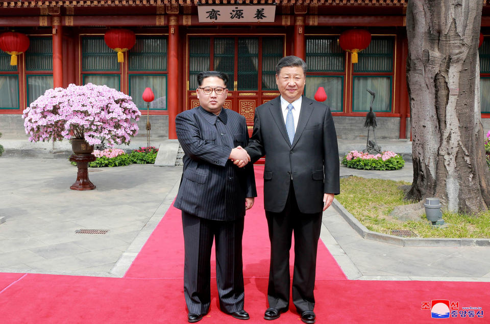Kim and Xi shake hands at the Diaoyutai State Guesthouse on March 27; Kim waves from his armored train before departing Beijing following his surprise visit