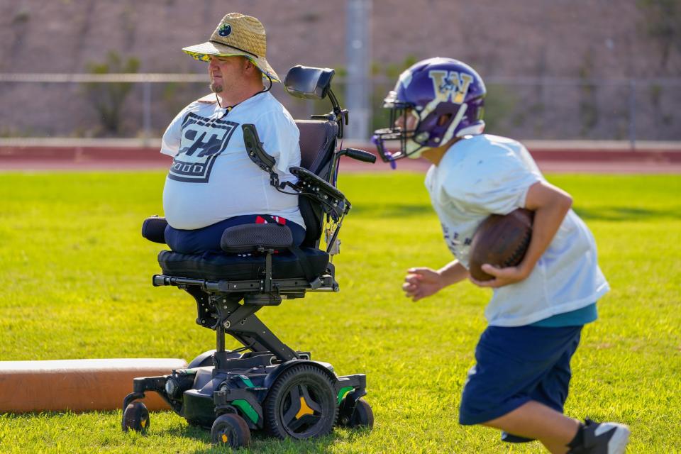 Wickenburg High School assistant football coach Carter Crosland (left) runs drills during practice at the school's football field.