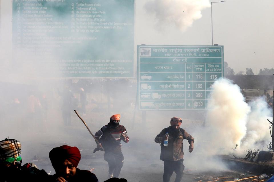 Protesting farmers run for cover as Indian Police fires teargas to prevent them from moving towards Delhi on the second day of their protest at Shambhu Haryana-Punjab border point (EPA)