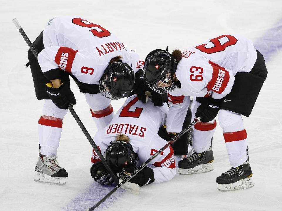 Julia Marty (6) and Anja Stiefel of Switzerland (63) check on their injured teammate Lara Stalder during the third period of the game against USA at the 2014 Winter Olympics women's ice hockey match at Shayba Arena, Monday, Feb. 10, 2014, in Sochi, Russia. (AP Photo/Petr David Josek)