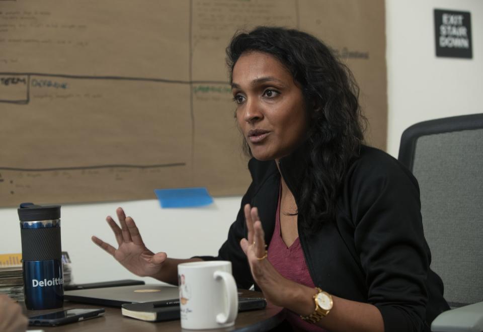 Nithya Raman speaks and gestures with her hands while seated at a table with a coffee cup and laptop in front of her.