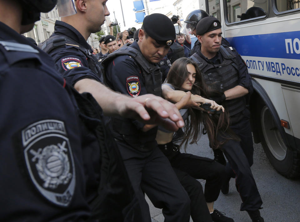 Police officers detain a woman prior to an unsanctioned rally in the center of Moscow, Russia, Saturday, July 27, 2019. OVD-Info, an organization that monitors political arrests, said about 50 people had been detained by 1:30 p.m. Saturday (1030 GMT), a half-hour before the protest against the exclusion of opposition figures from the ballot for city council elections was to start. (AP Photo/Alexander Zemlianichenko)