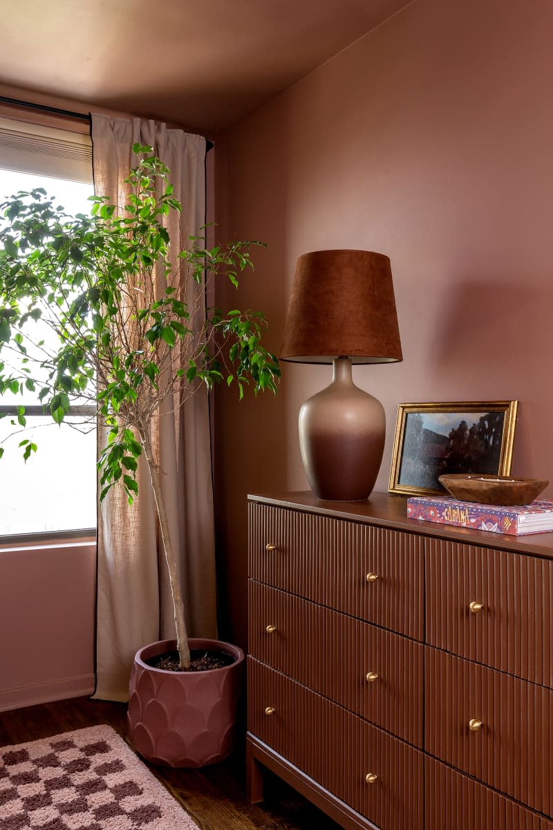 Lamp on dresser in dusty pink bedroom.