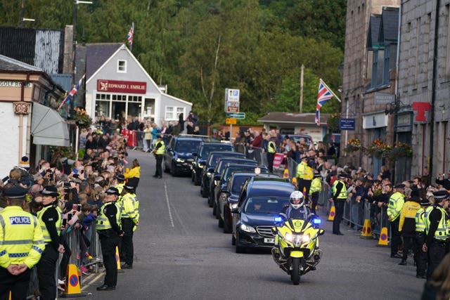 The hearse carrying the coffin of Queen Elizabeth II, draped with the Royal Standard of Scotland, passing through Ballater as it continues its journey to Edinburgh from Balmoral