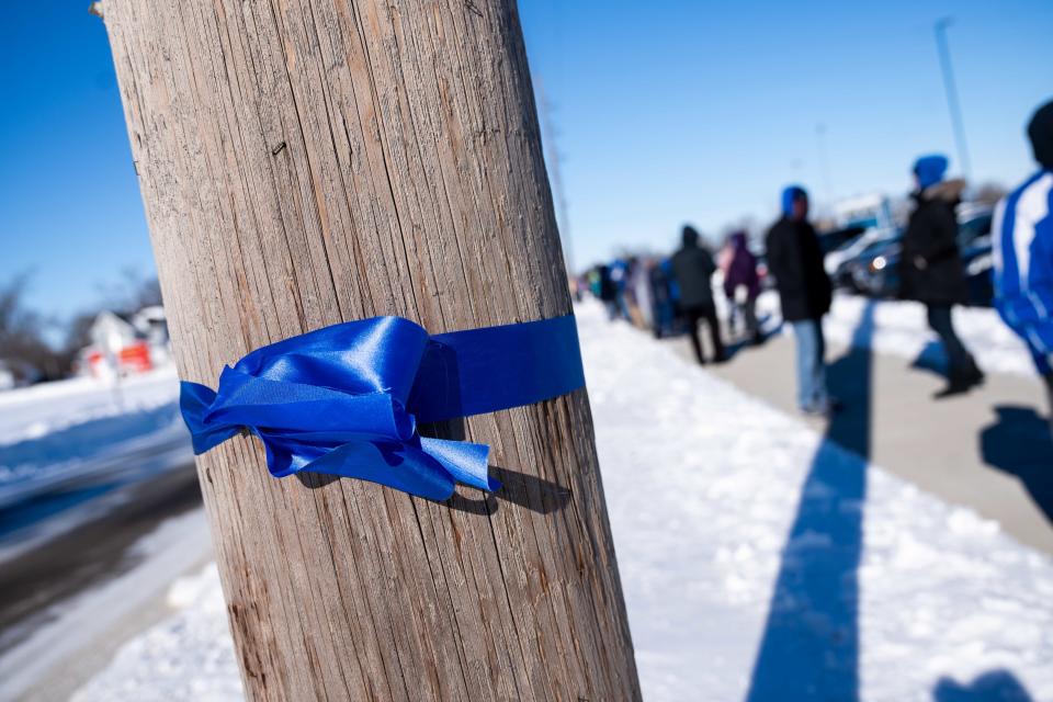 Blue ribbon is tied around telephone poles to honor the victims of the Perry school shooting Tuesday, Jan. 16, 2024, in Perry, IA.