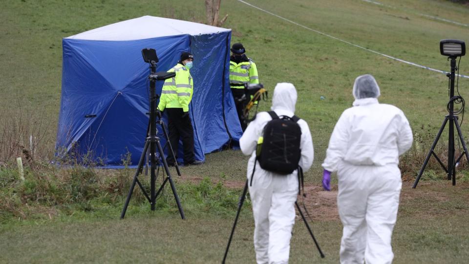 Zwei Gerichtsmediziner gehen zu einem Zelt am Tatort auf dem Bugs Bottom Feld. Fünf Jugendliche sollen hier im Januar einen 13-jährigen Jungen erstochen haben.