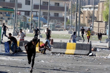 Demonstrators run at a protest during a curfew, three days after the nationwide anti-government protests turned violent, in Baghdad