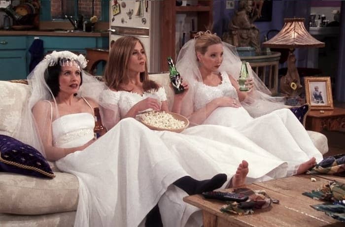 Three women in wedding dresses on the couch.