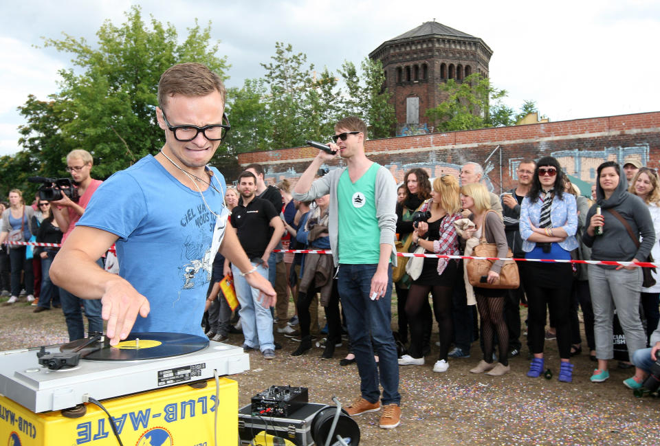BERLIN, GERMANY - JULY 21: A contestant competes in the "Vinyl Record Spinning Contest," in which competitors must run around a record player while keeping a finger on a record, at the second annual Hipster Olympics on July 21, 2012 in Berlin, Germany. With events such as the "Horn-Rimmed Glasses Throw," "Skinny Jeans Tug-O-War," "Vinyl Record Spinning Contest" and "Cloth Tote Sack Race," the Hipster Olympics both mocks and celebrates the Hipster subculture, which some critics claim could never be accurately defined and others that it never existed in the first place. The imprecise nature of determining what makes one a member means that the symptomatic elements of adherants to the group vary in each country, but the archetype of the version in Berlin, one of the more popular locations for those following its lifestyle, along with London and Brooklyn, includes a penchant for canvas tote bags, the carbonated yerba mate drink Club Mate, analogue film cameras, asymmetrical haircuts, 80s neon fashion, and, allegedly, a heavy dose of irony. To some in Berlin, members of the hipster "movement" have replaced a former unwanted identity in gentrifying neighborhoods, the Yuppie, for targets of criticism, as landlords raise rents in the areas to which they relocate, particularly the up-and-coming neighborhood of Neukoelln. (Photo by Adam Berry/Getty Images)