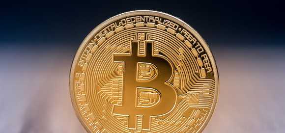 A physical gold coin marked with the bitcoin B.